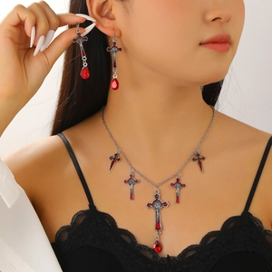 Close-up of gothic necklace and earrings set featuring red crosses on female model