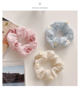 Detail of elegant camellia hair scrunchies in pink, blue, and cream with rose accents