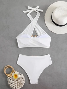 Flat lay of white high-waisted bikini with gold buckle and vacation accessories
