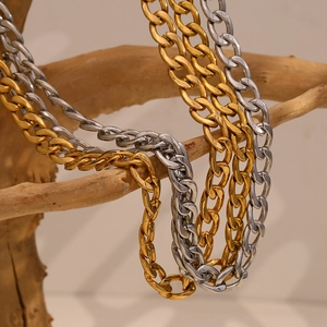 Artistic display of gold and silver cuban link necklaces on a rustic wood branch