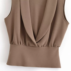 Detail of brown crossover V-neck sleeveless top with textured crepe fabric and pleated waist