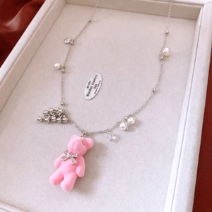 Close-up of pink flocked bear pendant necklace with pearls and silver chain in a jewelry tray