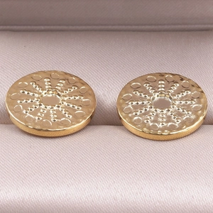 Macro detail of gold stainless steel sunburst earrings inside a soft jewelry box