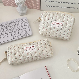 Vue détaillée de la trousse de maquillage à fleurs et du plumier assorti sur le bureau