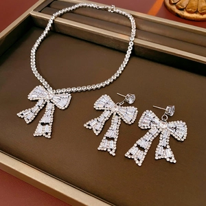 Macro shot of silver bow jewelry set with sparkling rhinestones in a brown tray