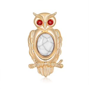 Detail of owl brooch with gold finish, red rhinestone eyes and marble effect stone