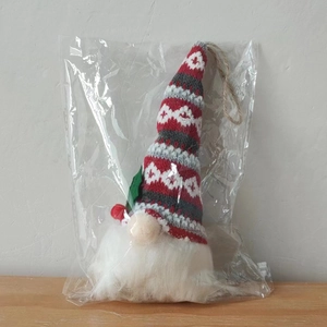 Detail of Christmas gnome plush ornament in plastic packaging with knitted hat and rope loop