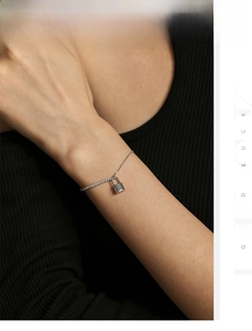 Detail of silver S925 padlock pendant bracelet on model wrist with fine link chain