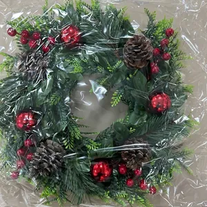 Détail d'une couronne de Noël avec baies rouges et pommes de pin sous emballage