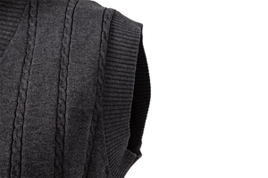 Nahaufnahme der grauen Strickweste mit detailliertem Zopfmuster und Rippstrick-Armloch