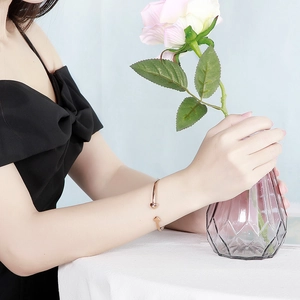 Bracelet jonc ouvert en forme de cœur en or rose sur le poignet d'un mannequin
