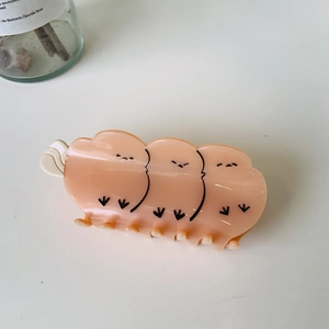 Detailed view of an orange cartoon chick hair claw clip made of glossy resin material