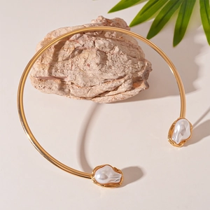 Detailed shot of golden metal choker with baroque pearls on a natural stone base