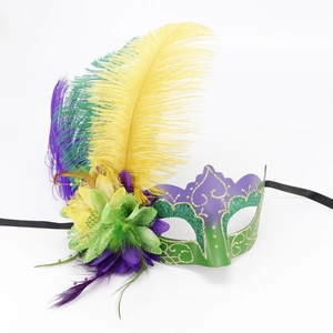 Detail of masquerade mask featuring vibrant feathers, gold glitter, and silk flower deco