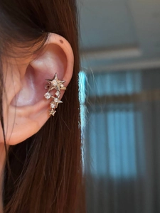 Macro shot of silver star ear cuff with sparkling crystals worn on a model's ear cartilage