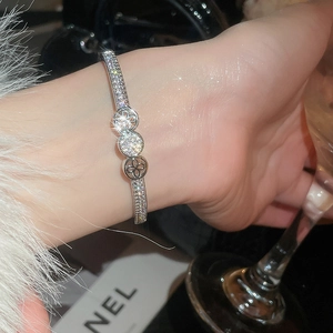 Macro detail of silver-plated zircon clover bangle worn against a luxury party backdrop