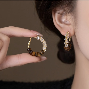 Detailed close-up of tiger eye stone earrings with silver needle and zircon accents