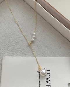 Detail of s925 silver fringe necklace featuring lustrous white pearls on a gold chain