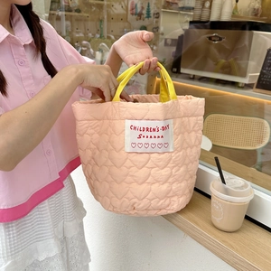 Détail du matelassage en cœur et des poignées jaunes sur le sac rose