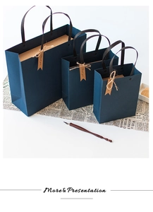 Trois sacs cadeaux bleu marine de tailles variées avec anses en satin et étiquettes