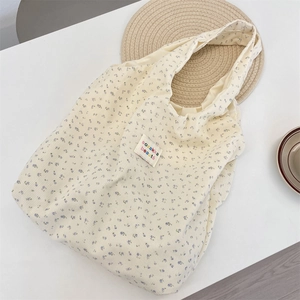 Detail of corduroy tote bag with blue floral pattern and embroidered textile label