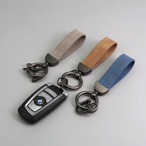 Three premium suede leather car keychains in grey, brown, and blue with gunmetal hardware