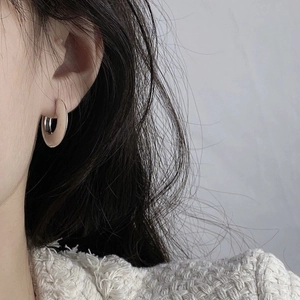 Minimalist beige resin hoop earrings with silver metal details worn by model