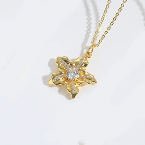 Macro view of a gold flower pendant necklace with central stone and zircon details