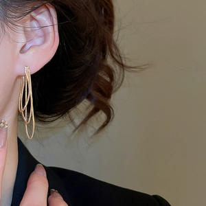 Détail de boucles d'oreilles élégantes à triple chaîne dorée portées sur un mannequin