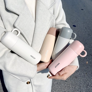 Detail of colorful insulated water bottles with ring handles in a warm lifestyle setting