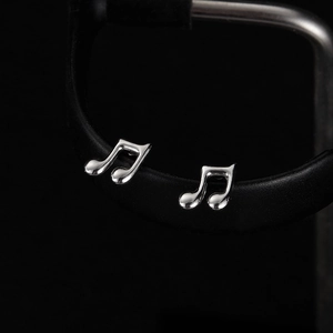 Macro shot of silver musical note stud earrings in polished stainless steel on a black stand