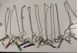 Macro detail of twisted bar pendants in silver and iridescent rainbow finish on steel chains