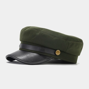 Detail of vintage dark green newsboy cap with black faux leather brim and gold buckle