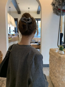 Dettaglio di una molletta a cuore con glitter neri e perle su un'acconciatura a chignon