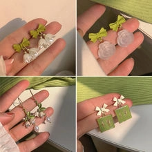 Detail of cute claw and floral earrings featuring lily of the valley and green ribbons