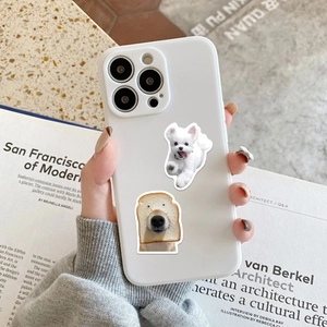Close-up of white iPhone case featuring funny realistic dog stickers and bread puppy meme