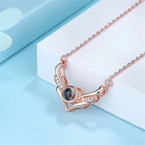 Detail of rose gold angel wing necklace with zircon and heart projection stone