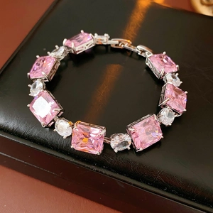 Detailed close-up of silver bracelet with pink rectangular zircons on black leather