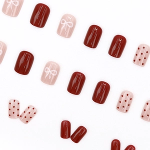 Short square false nails with red polka dots and white bow designs in glossy finish