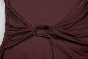 Macro shot of bronze wave metal ring buckle and ruched fabric on chocolate dress