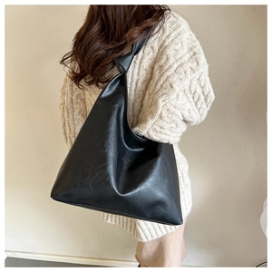 Close-up of black leather hobo bag featuring a stylish knotted shoulder strap detail