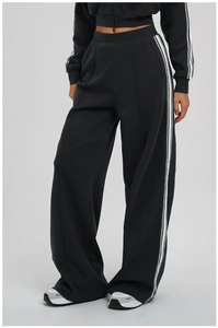 Detail of loose sports pants with white side stripes and centered pleat design