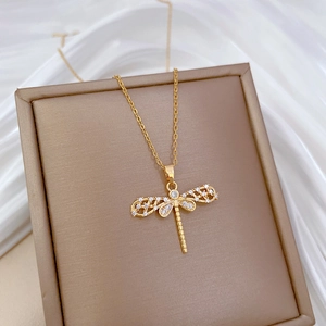 Elegant gold titanium dragonfly necklace with crystal pavé on a brown jewelry box