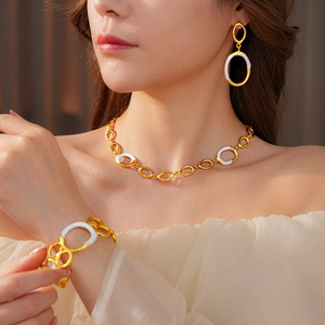 Close-up of gold and white enamel jewelry set including necklace, bracelet and earrings