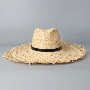 Detailed close-up of natural raffia straw weaving and raw frayed edges on the sun hat