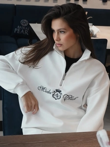 Detail of white half-zip sweatshirt featuring black Moda Club logo and ribbed texture