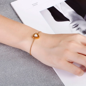 Détail du bracelet doré ajustable avec un pendentif triangle serti de cristaux brillants