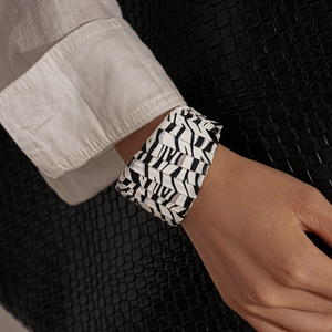 Detailed view of wide zebra print cuff bracelet with pleated texture on female wrist