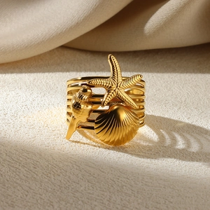 Detail of gold multilayer ring with decorative starfish and seashell motifs on a silk background
