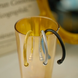 Detailed view of twisted steel wire cable bangles in gold, silver, and black finishes